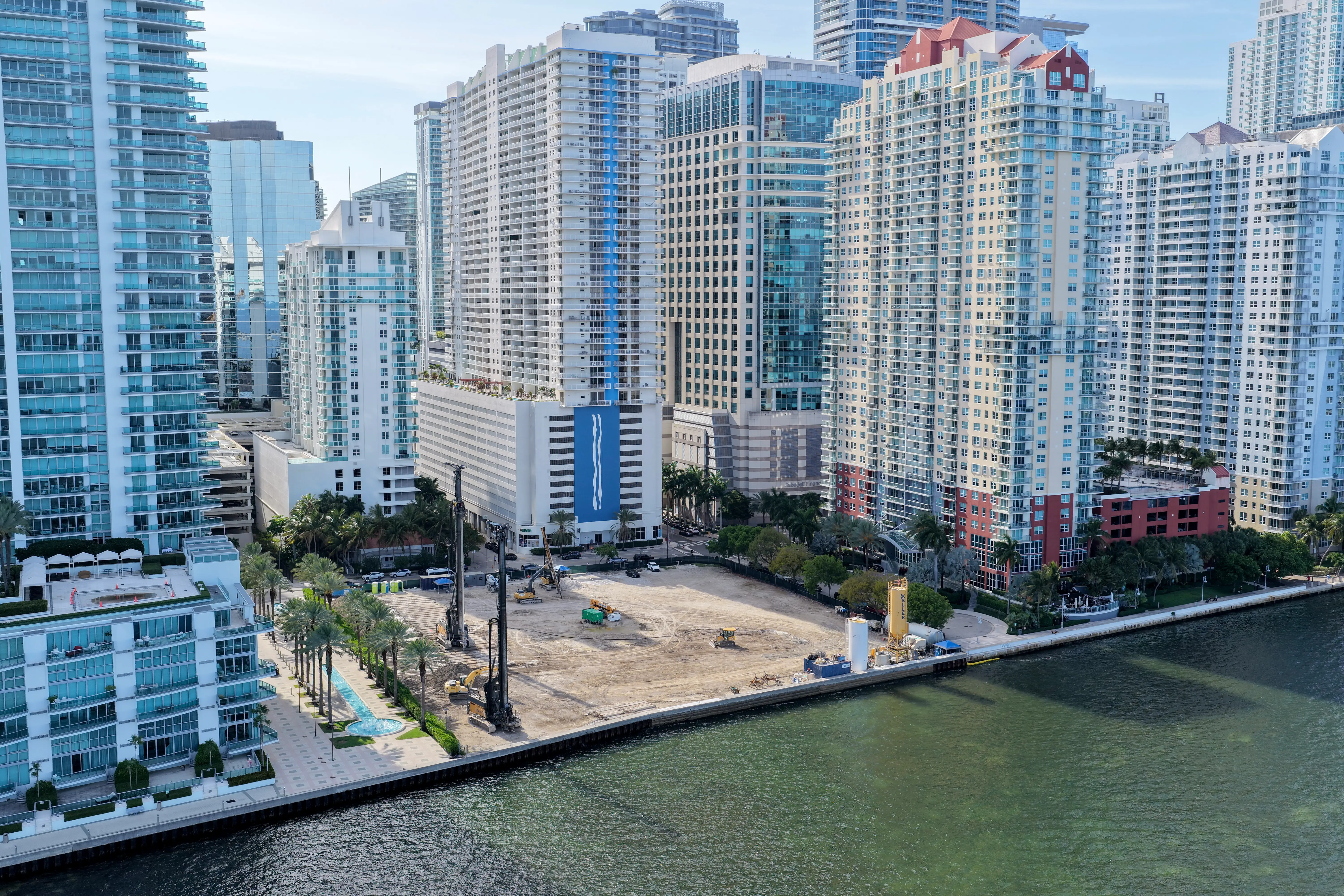 An aerial view of construction machinery on an empty waterfront lot in Miami.