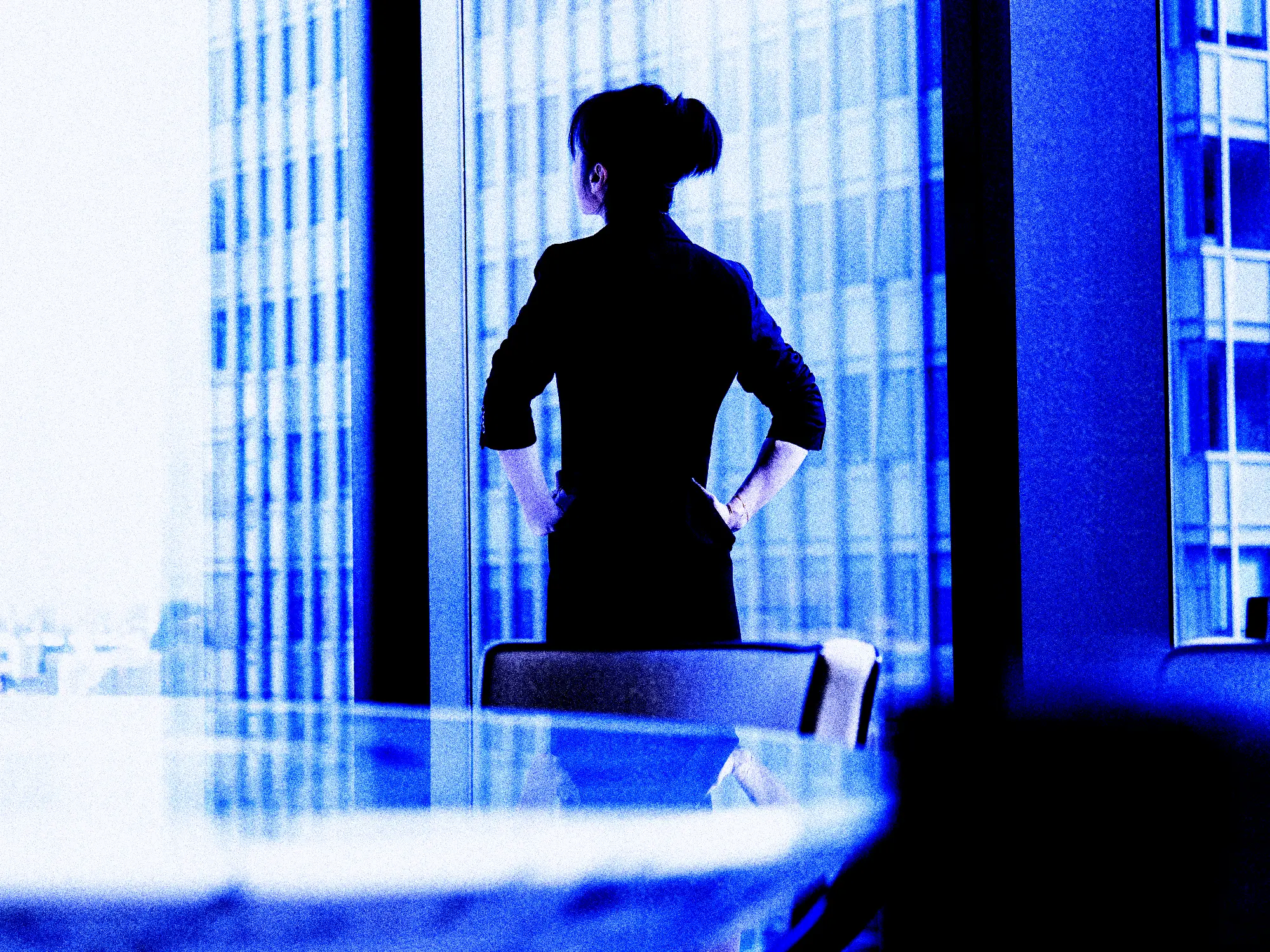 Rear view of asian businesswoman looking out conference room window.