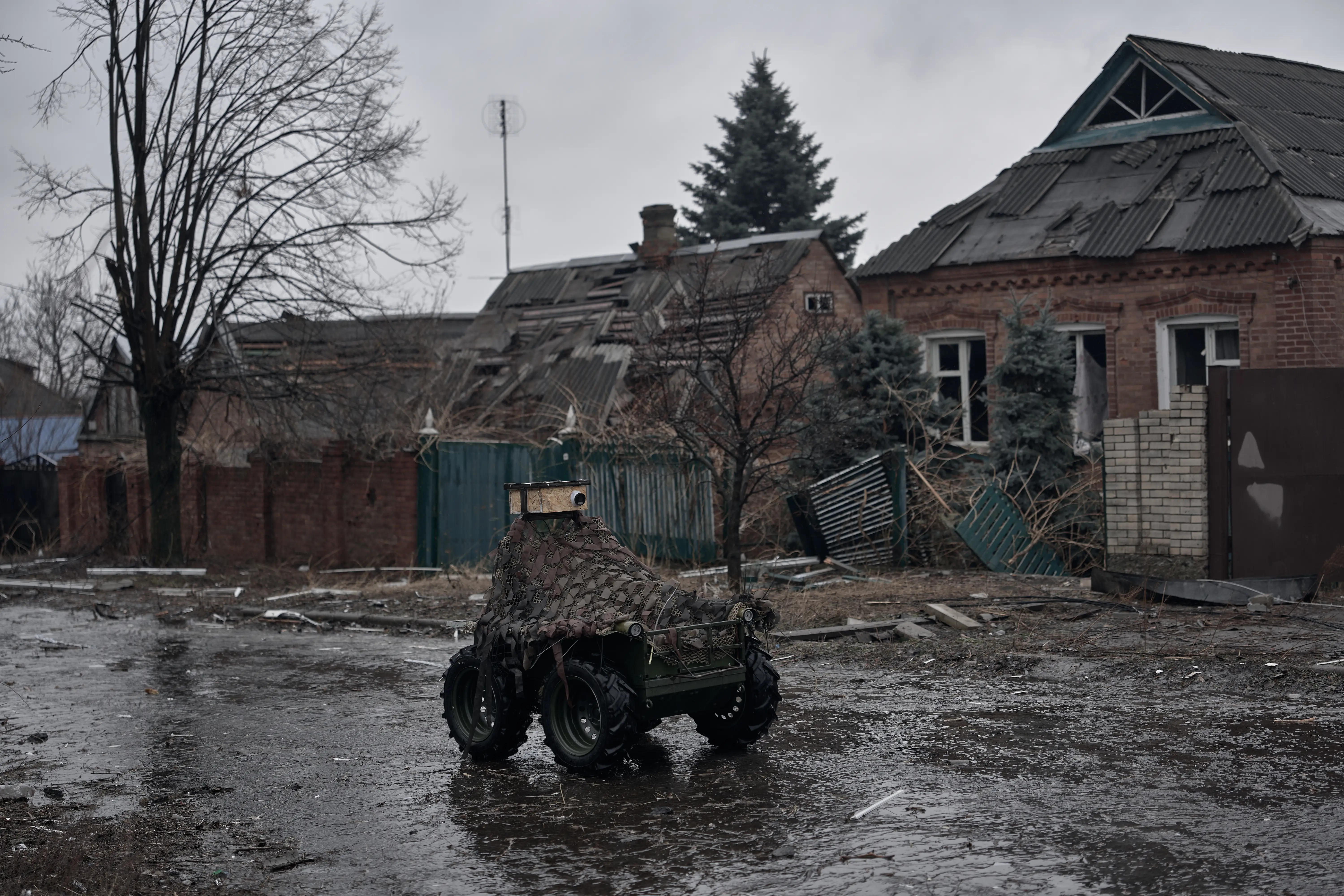 A small uncrewed buggy navigates the streets of a wartorn village.