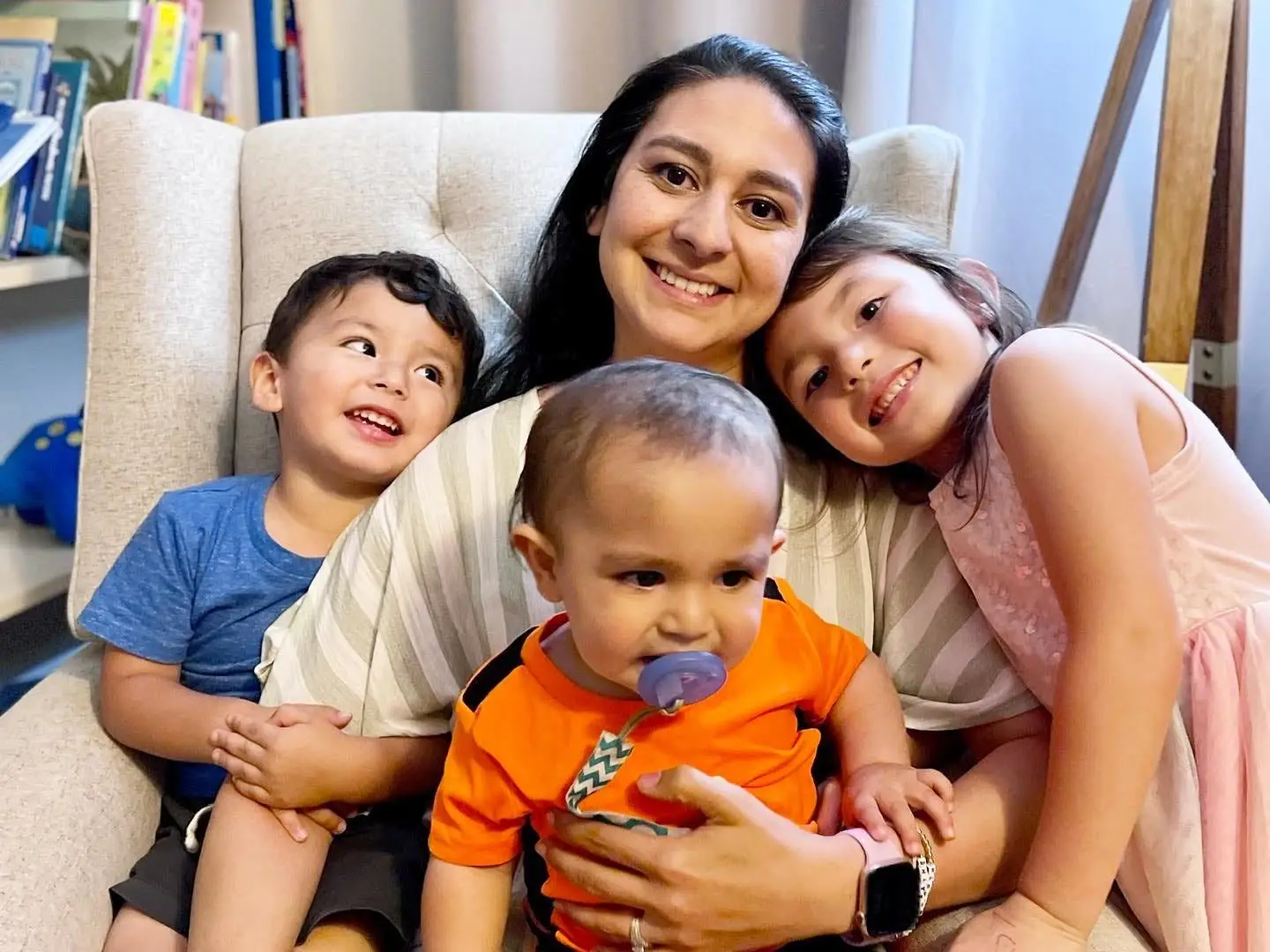 a mom sitting in an armchair with her 3 young kids