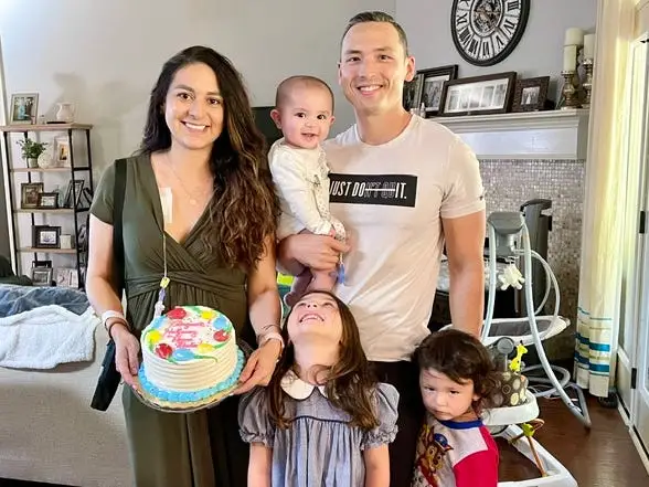 a family of five holding a birthday cake in their home.
