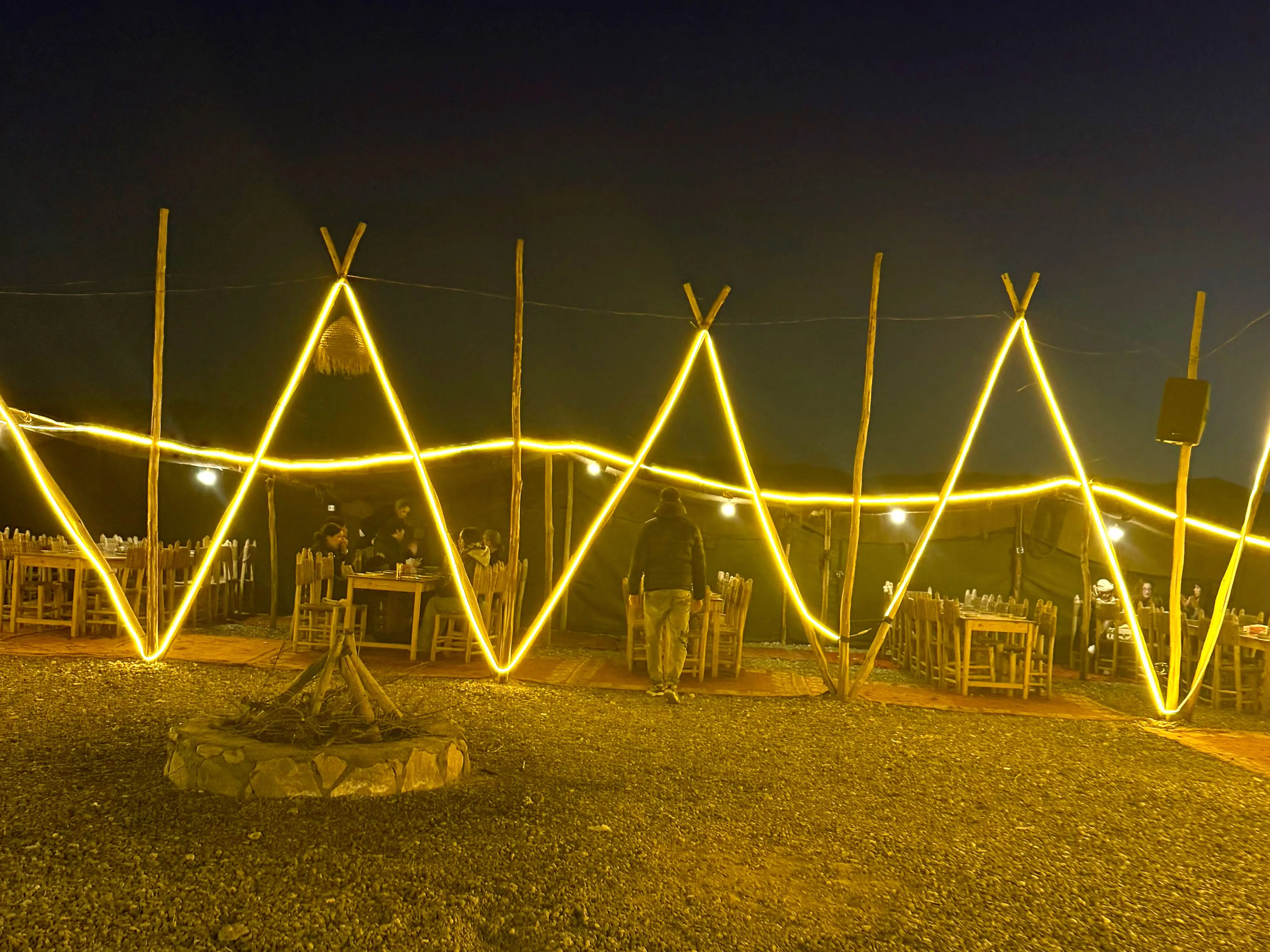 Long tables set up under a tent and neon lights.