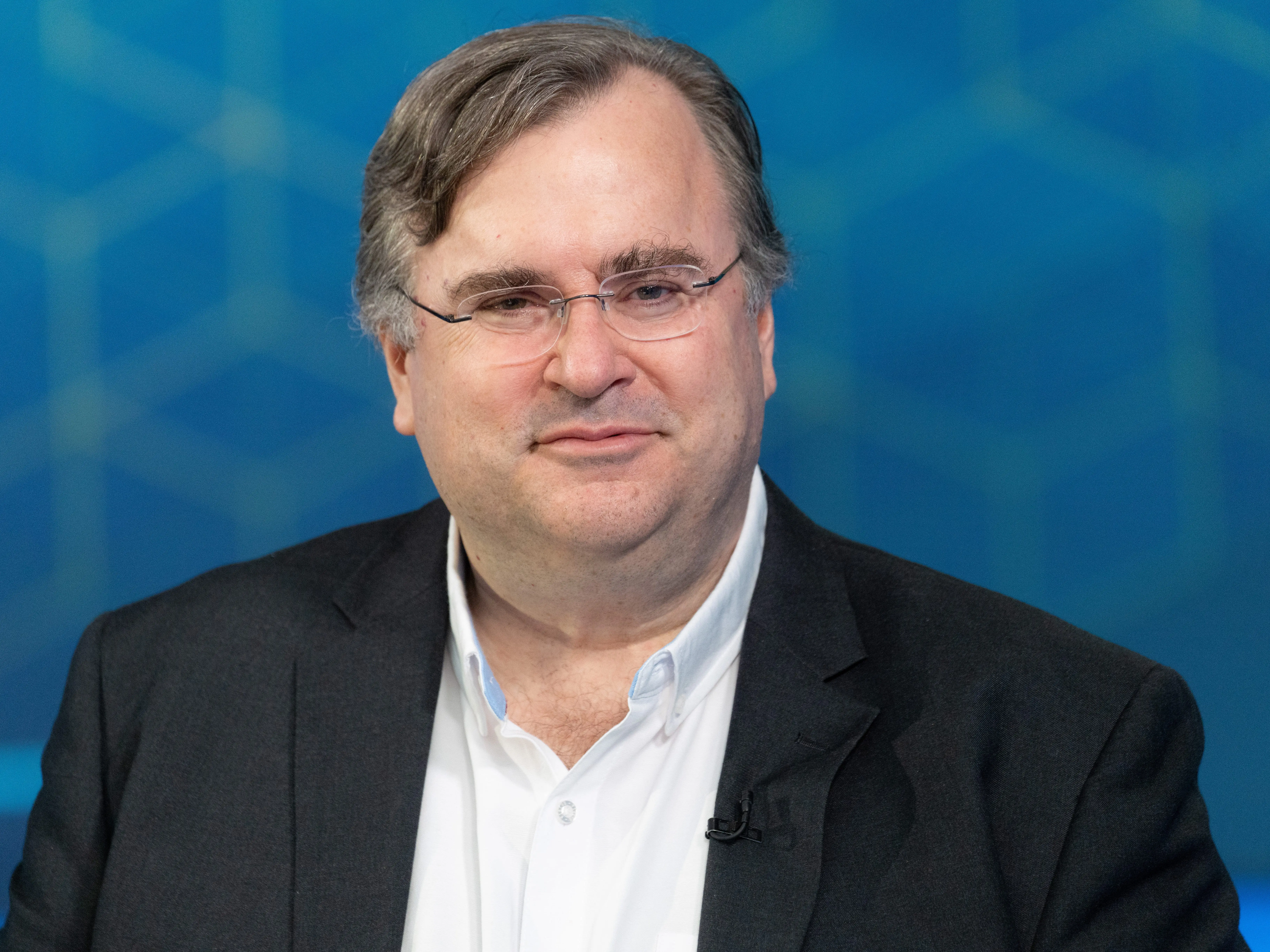 LinkedIn cofounder and Manas AI cofounder Reid Hoffman speaks on a panel against a blue backdrop.