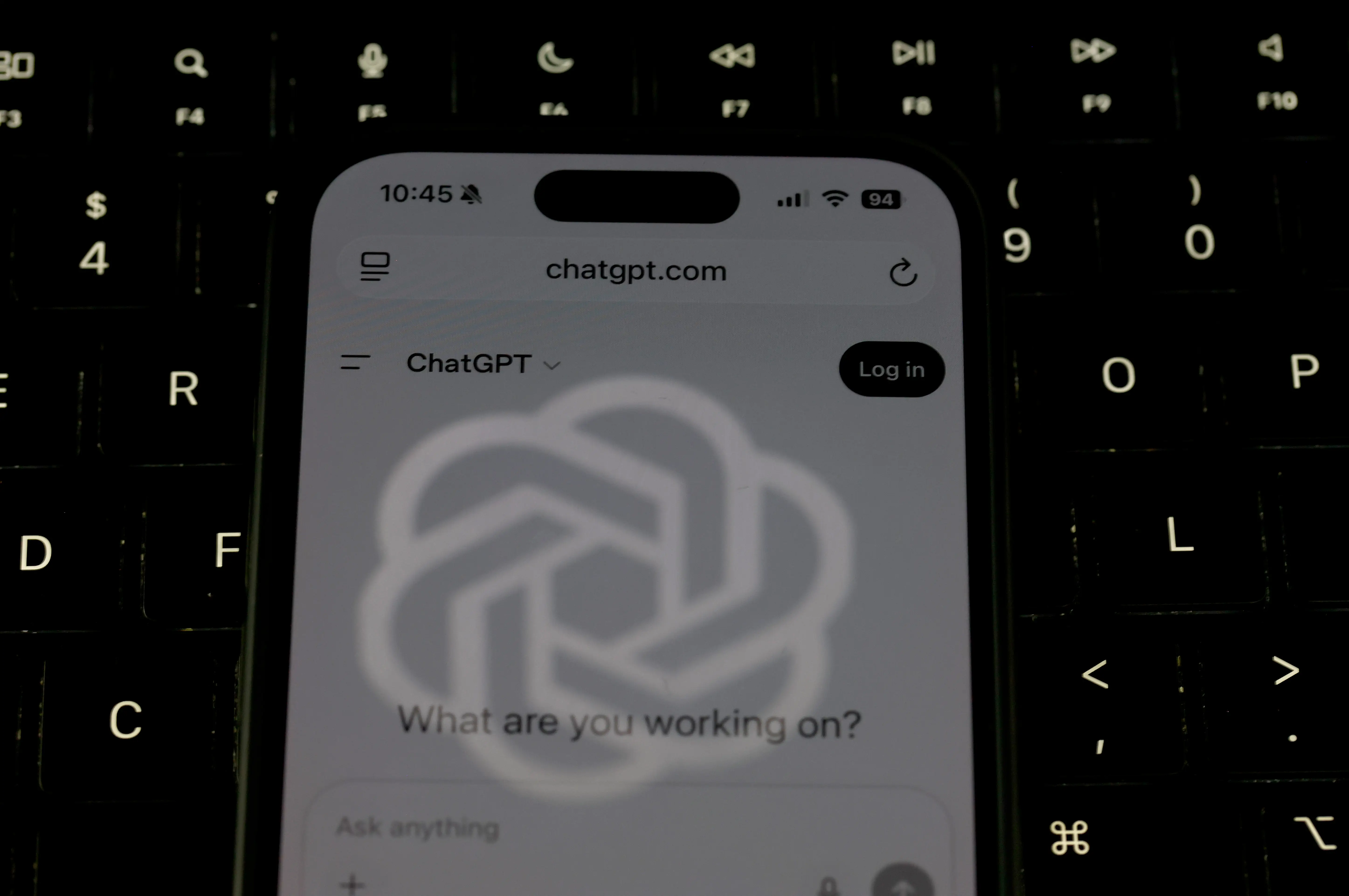 The OpenAI logo is reflected on the screen of a smartphone with the ChatGPT website.