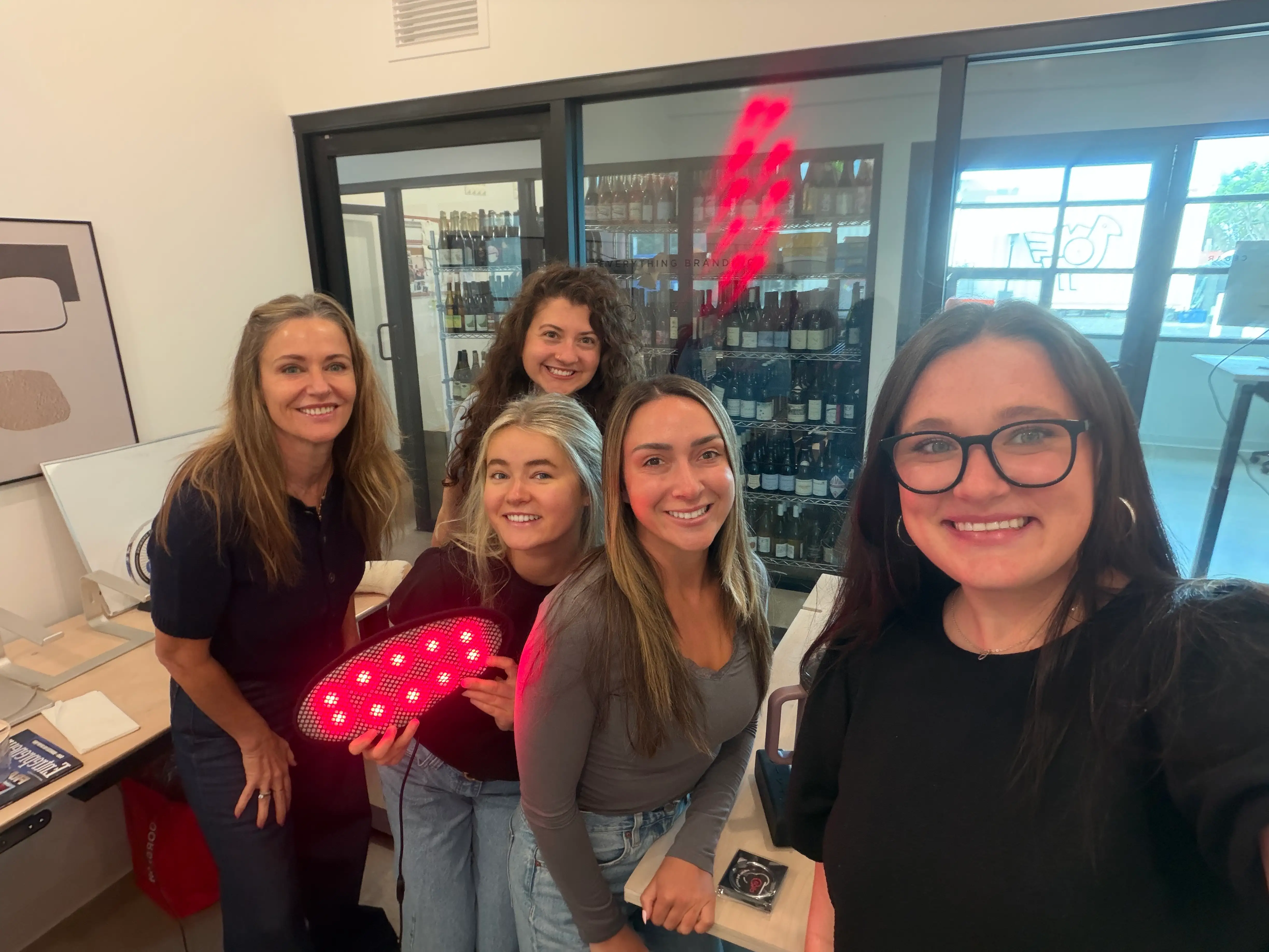 A group of women pose with an LED device.