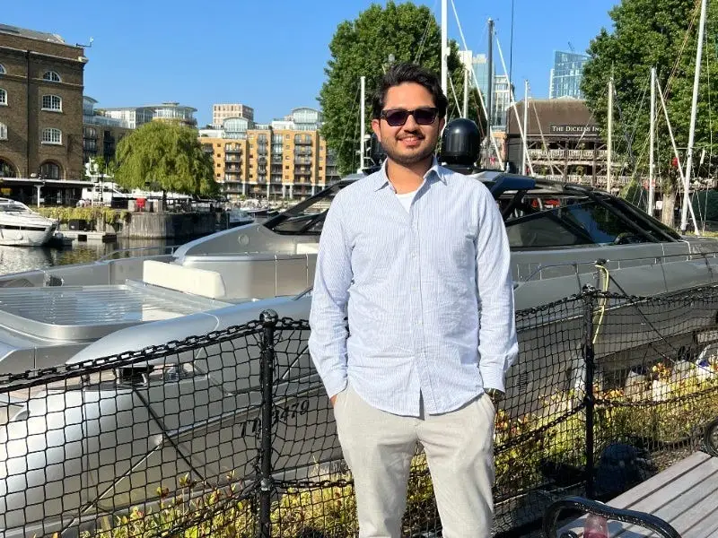 A man stands in front of a yacht.
