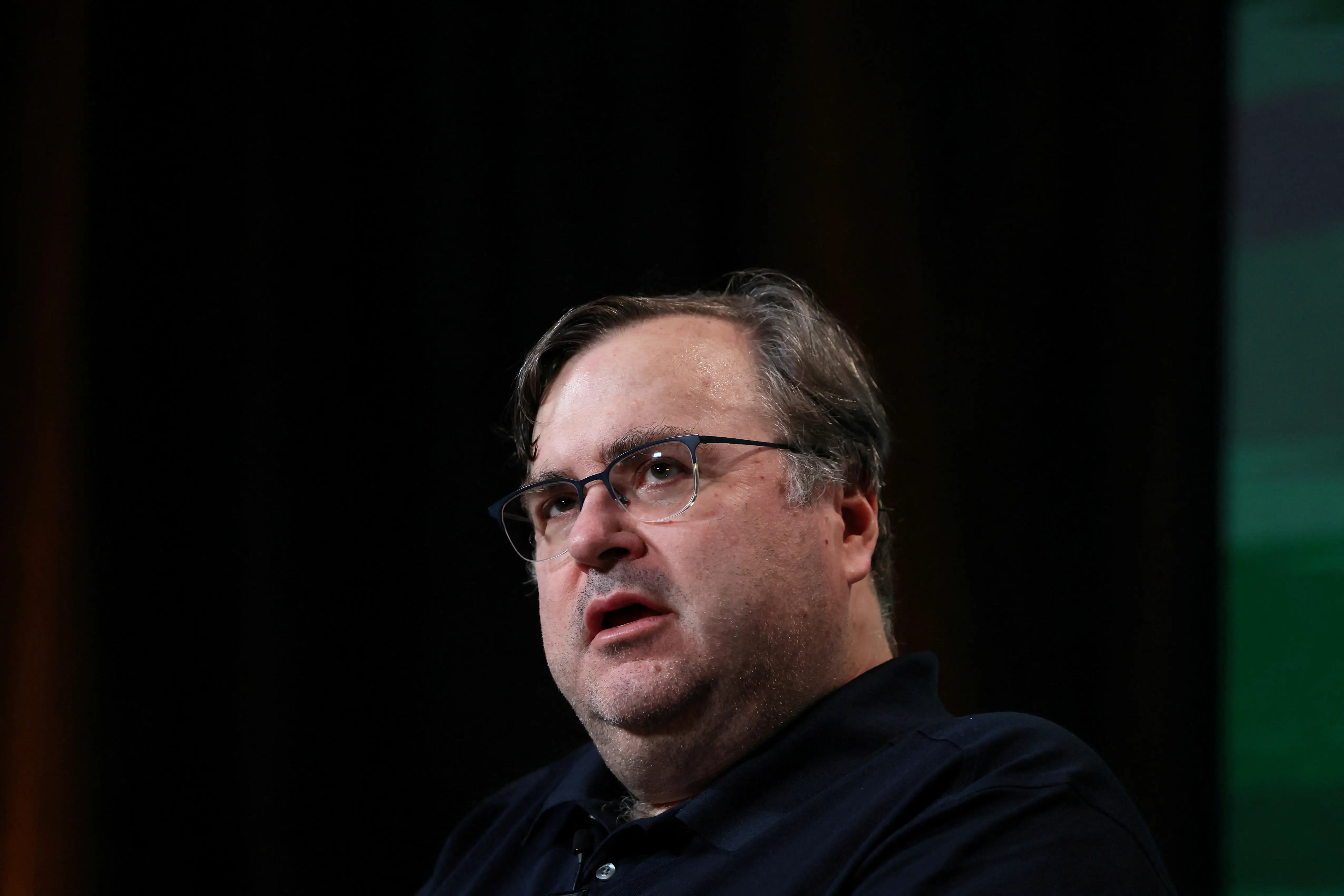 Reid Hoffman is onstage, dressed in a dark polo shirt.