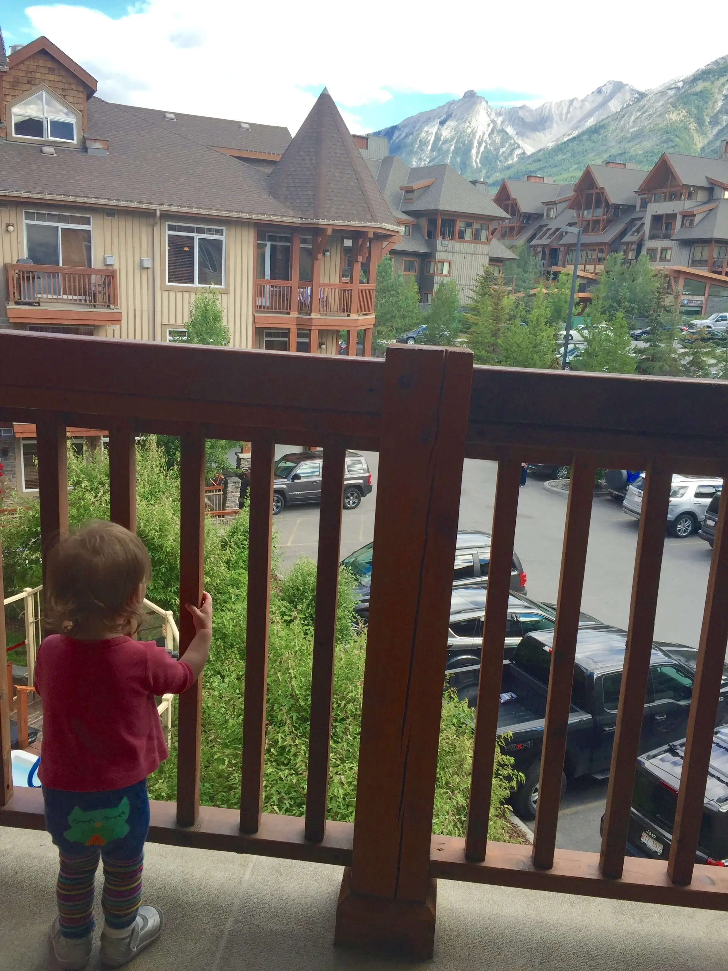 The author's young child looks out through a railing on a balcony.