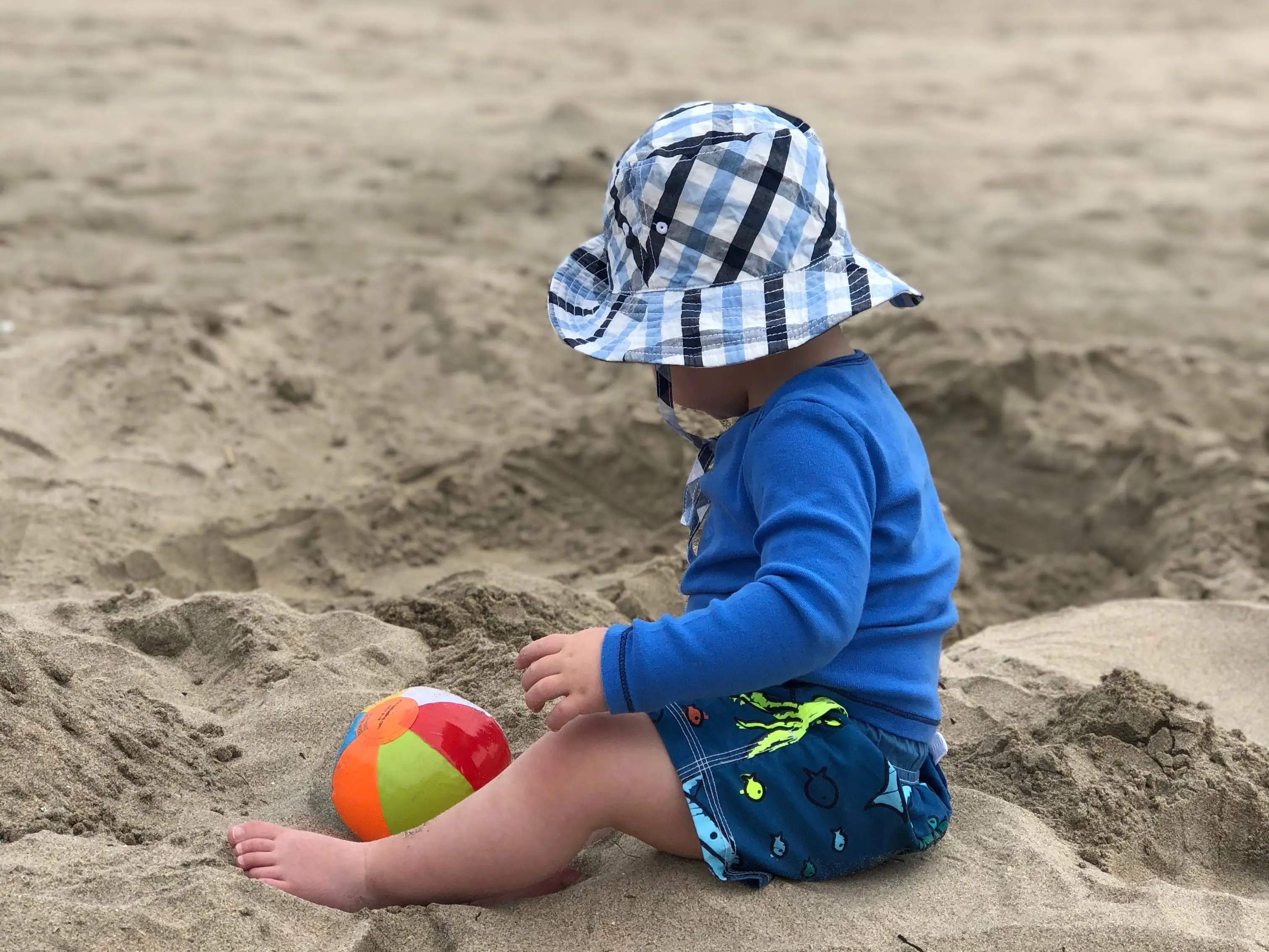 The author's young child plays in the sand on a beach.