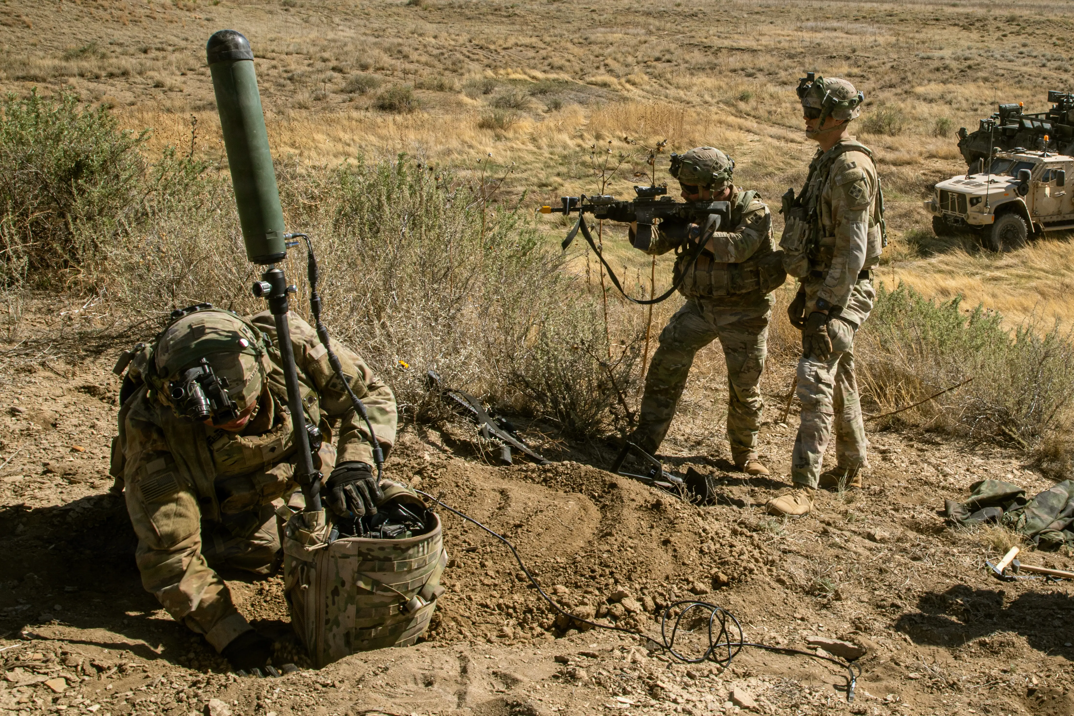 US soldiers stand in grasslands.