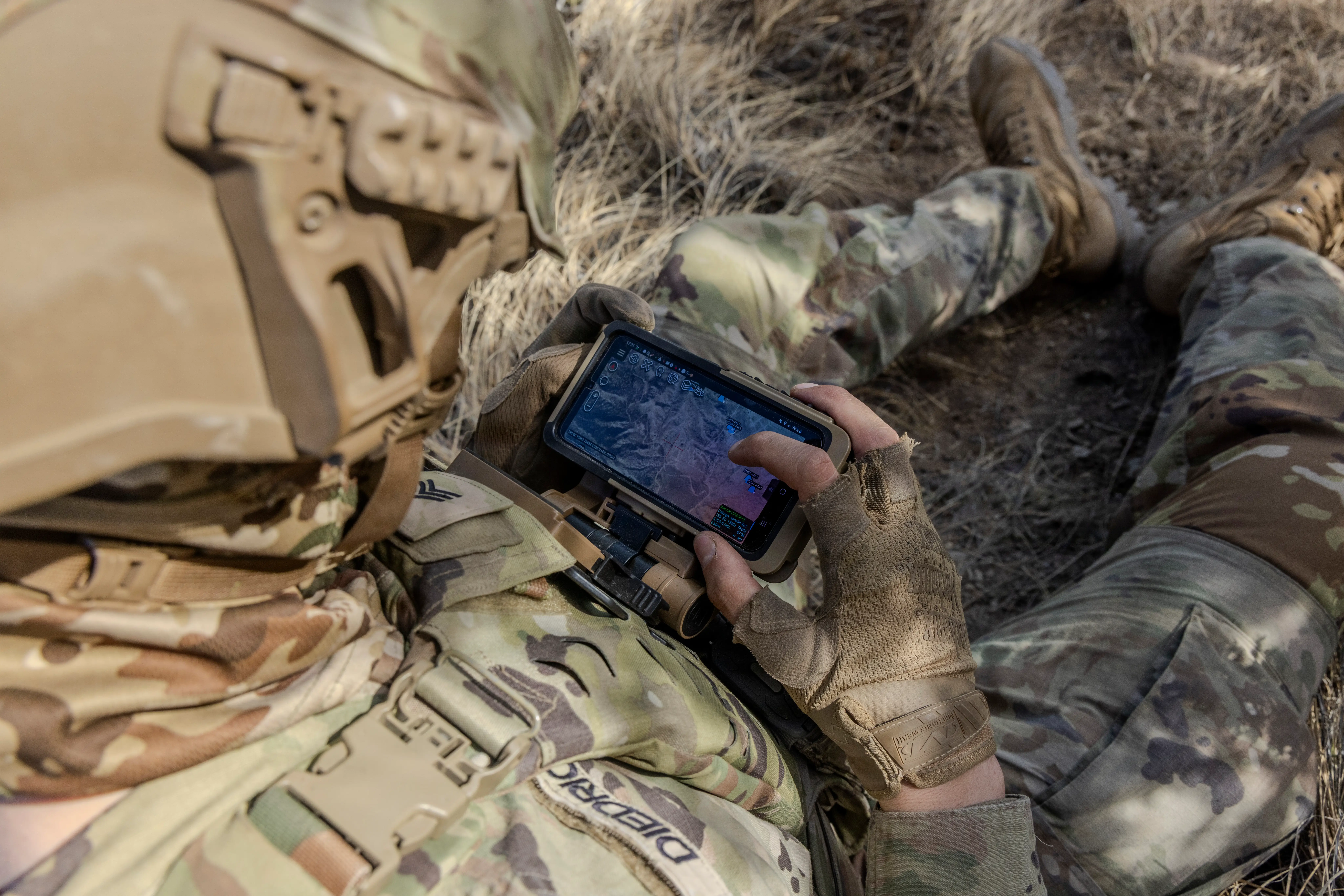 A US soldier looks down at a small tablet.