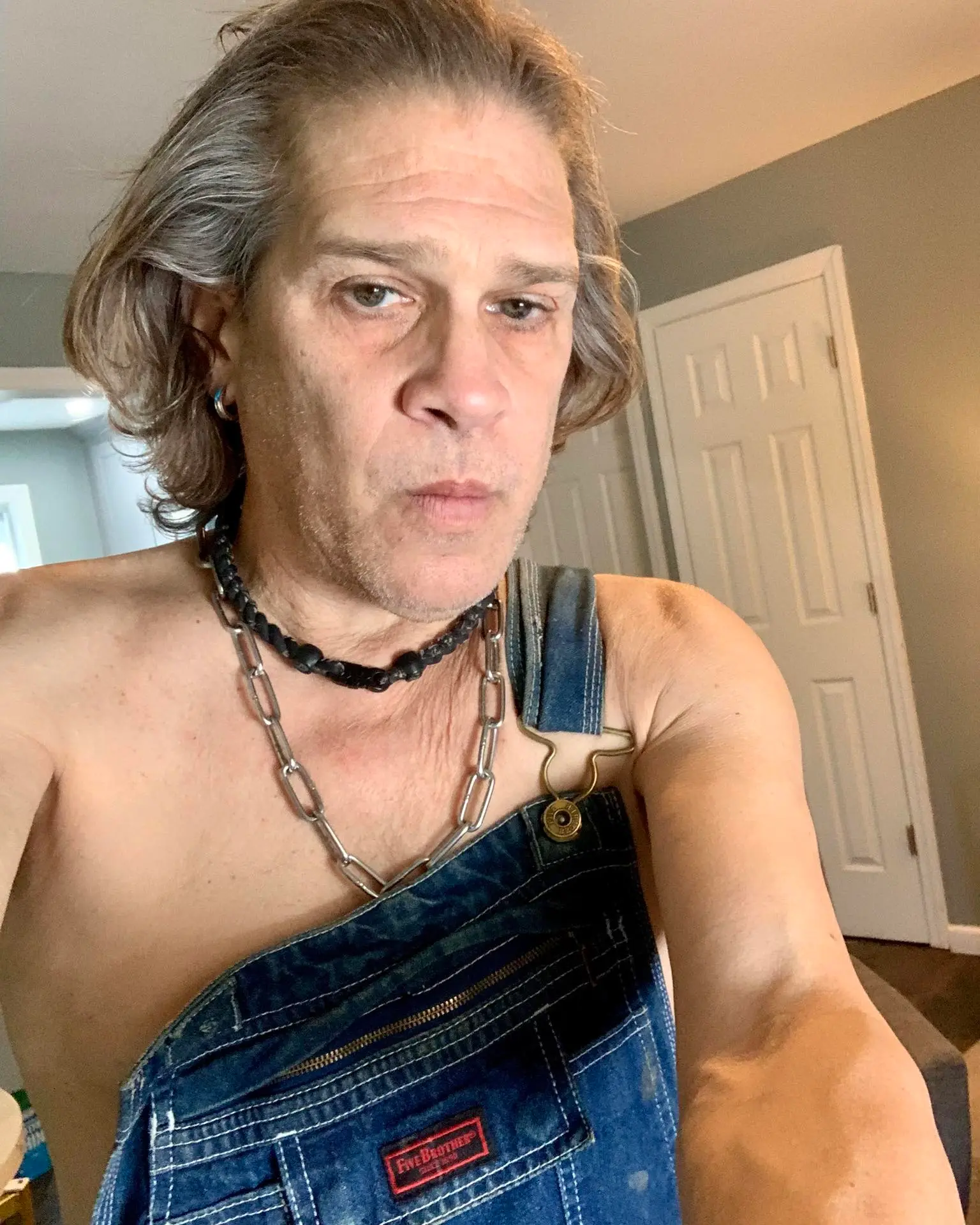 Jonathan Tiersten wearing overalls and two necklaces.