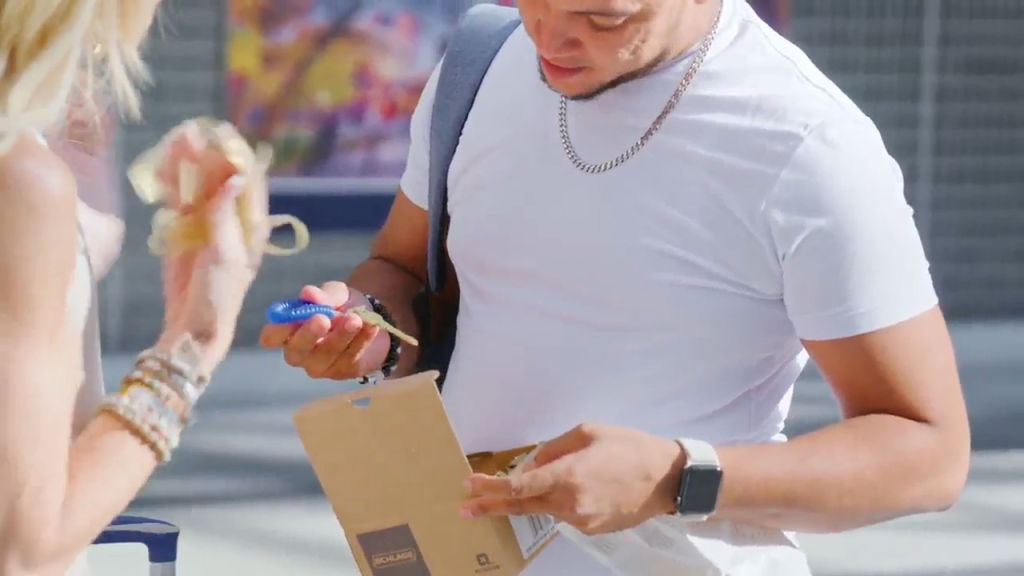 A man and woman examine a brown cardboard box with keys, including one with a blue cover.