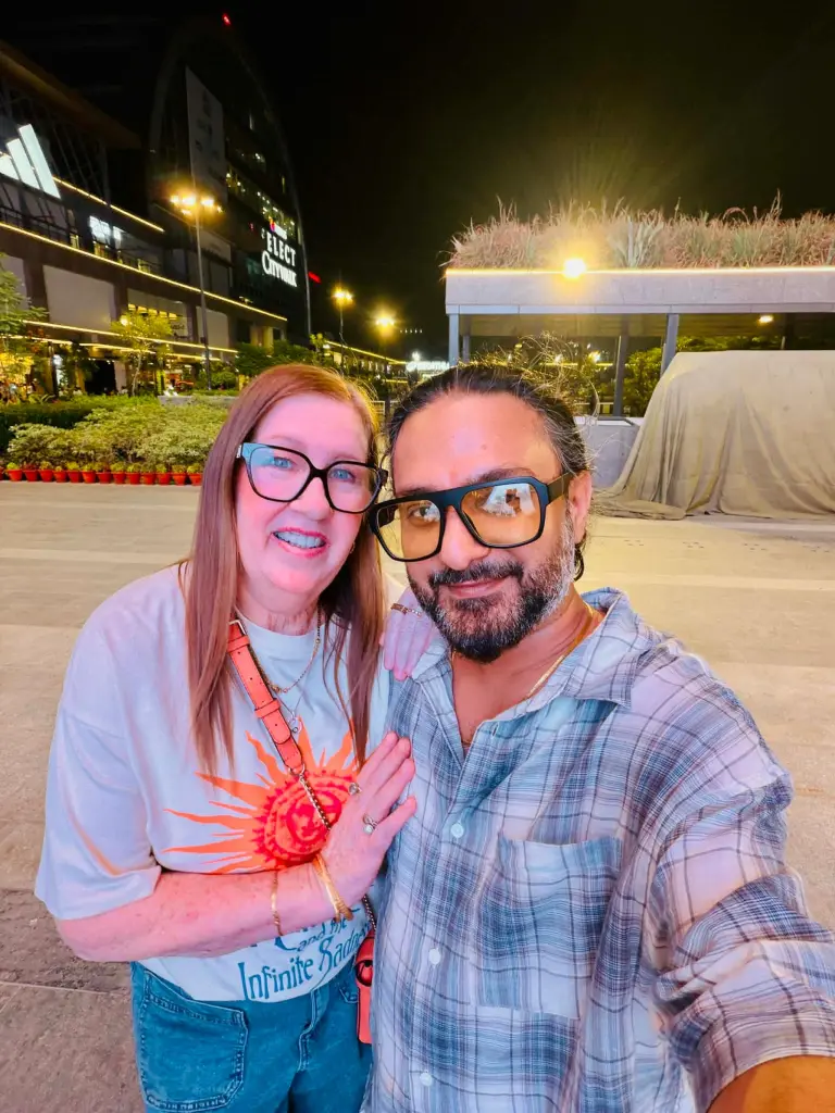 Jenny Slatten and Sumit taking a selfie at night in front of a building.