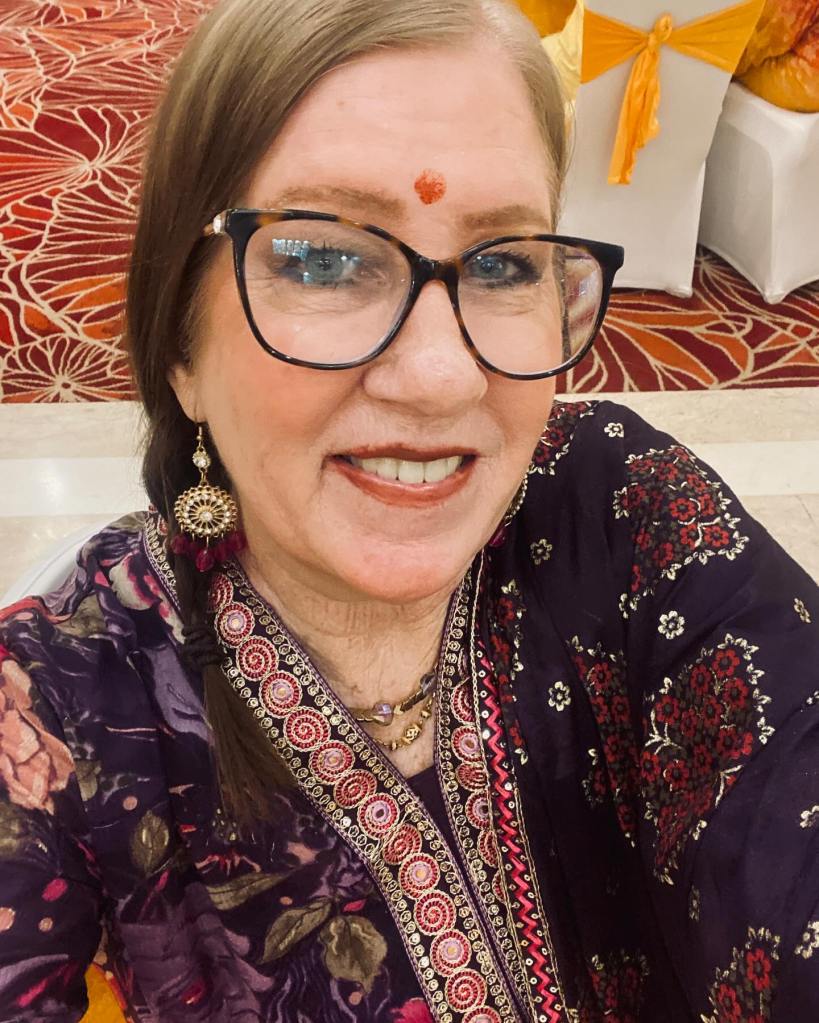 Jenny Slatten smiling in a patterned dress with a bindi on her forehead.