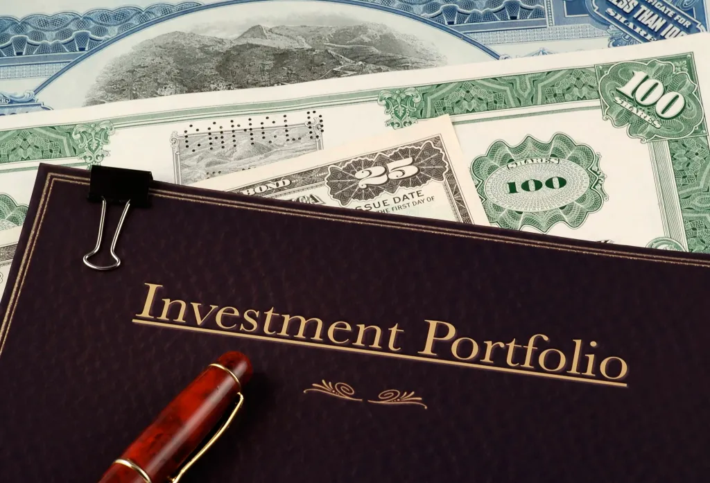 Investment portfolio folder with stock certificates, bonds, and a pen.