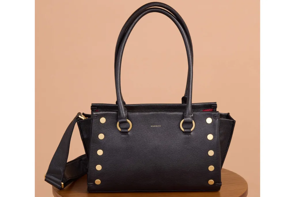 A black tote with gold studs, placed on a seat.