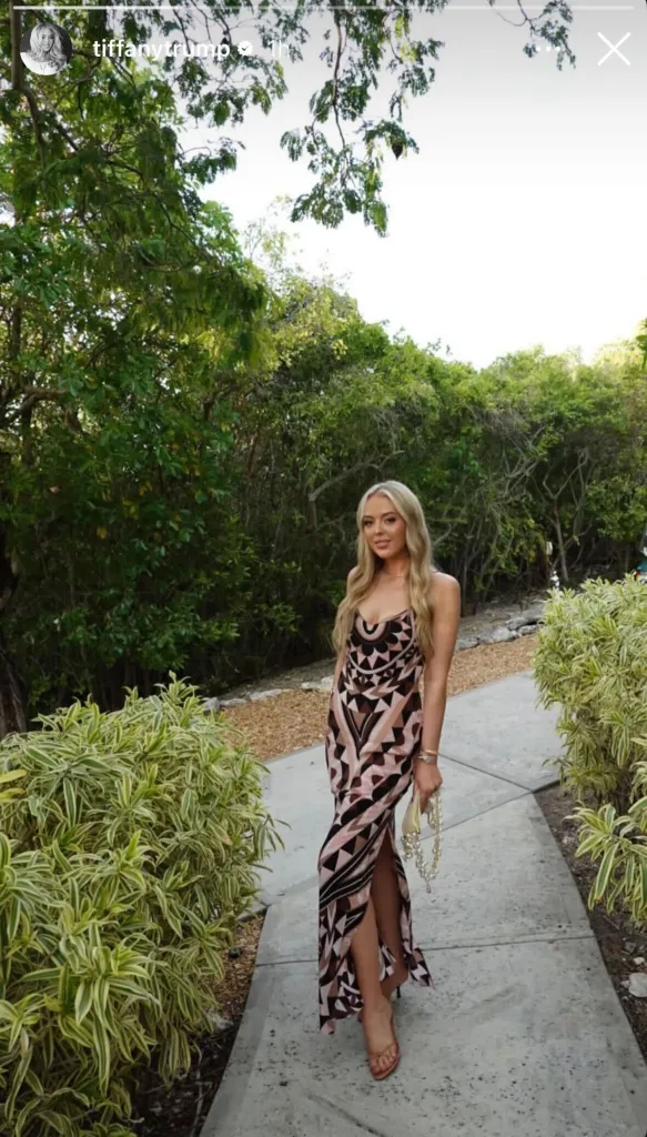 Tiffany Trump in a patterned dress walking on a path outdoors.