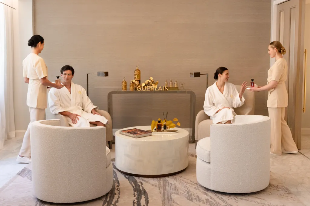 Two attendants serving products to a man and a woman in bathrobes at the Waldorf Astoria New York.