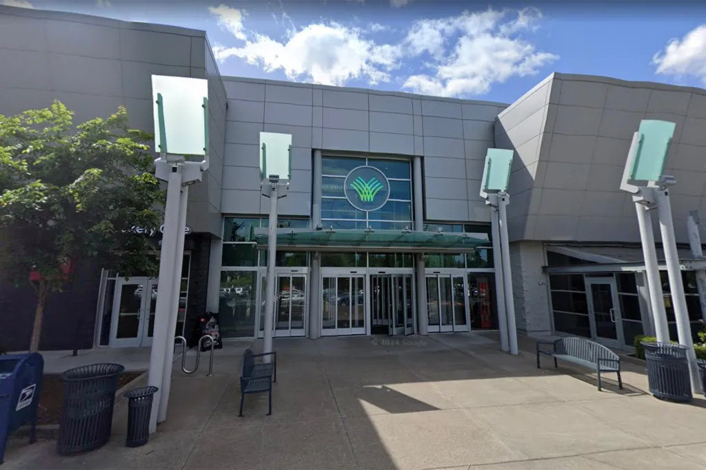 Exterior of a large building with a circular logo featuring green and blue intertwined shapes above the main entrance.