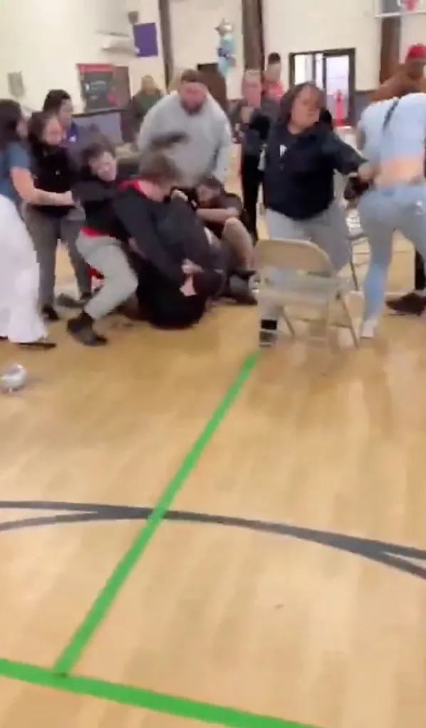 A chaotic scene where a group of people is engaged in a struggle on a wooden floor.