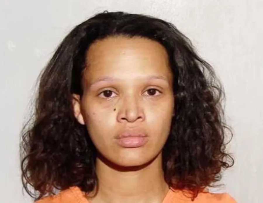 Woman with long, dark curly hair, brown eyes, and an orange shirt.