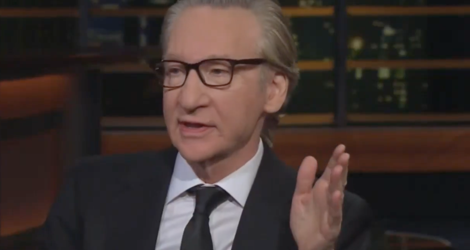 Bill Maher speaking with an animated hand gesture.