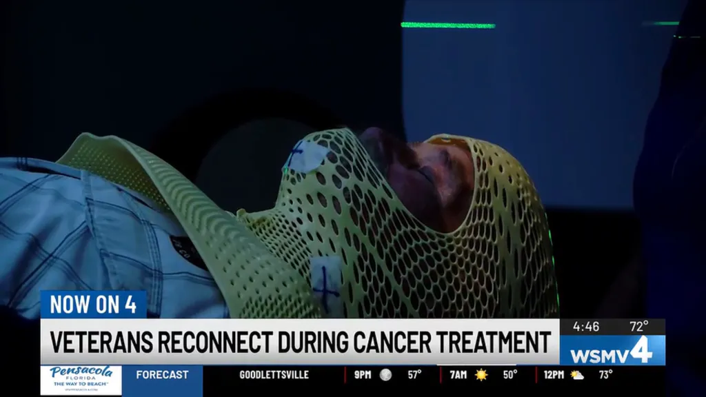 A patient with a green mesh mask covering their head undergoing cancer treatment.