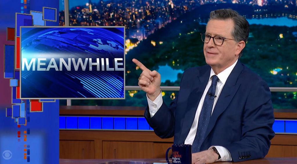 Stephen Colbert pointing at a screen displaying the word 