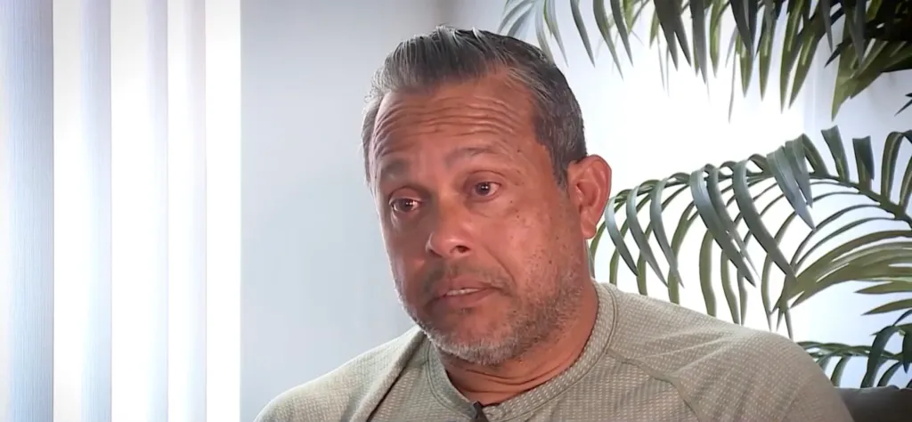 A man with graying hair and beard in a light green shirt.