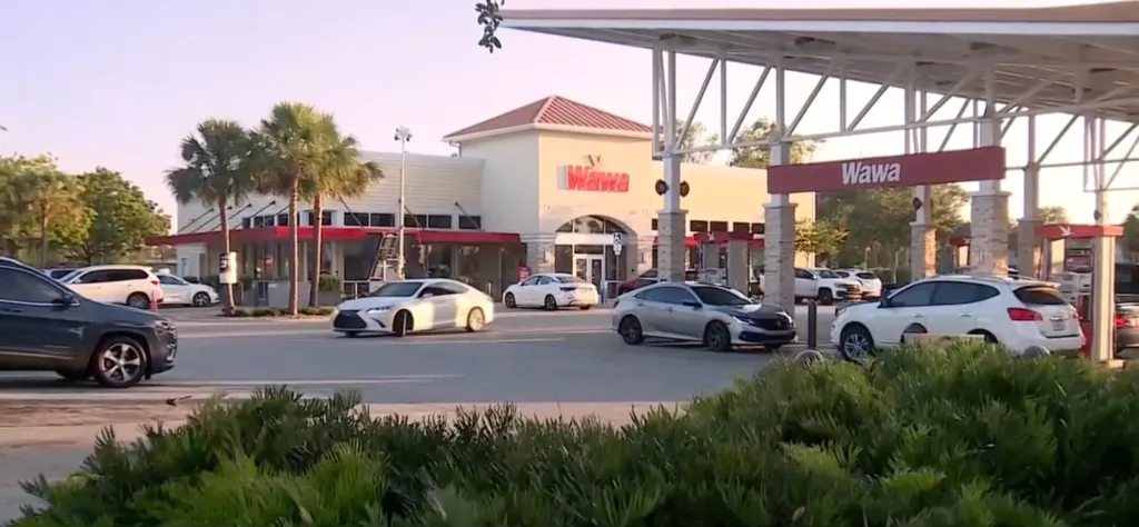 Wawa store and gas station with multiple cars parked and driving around.