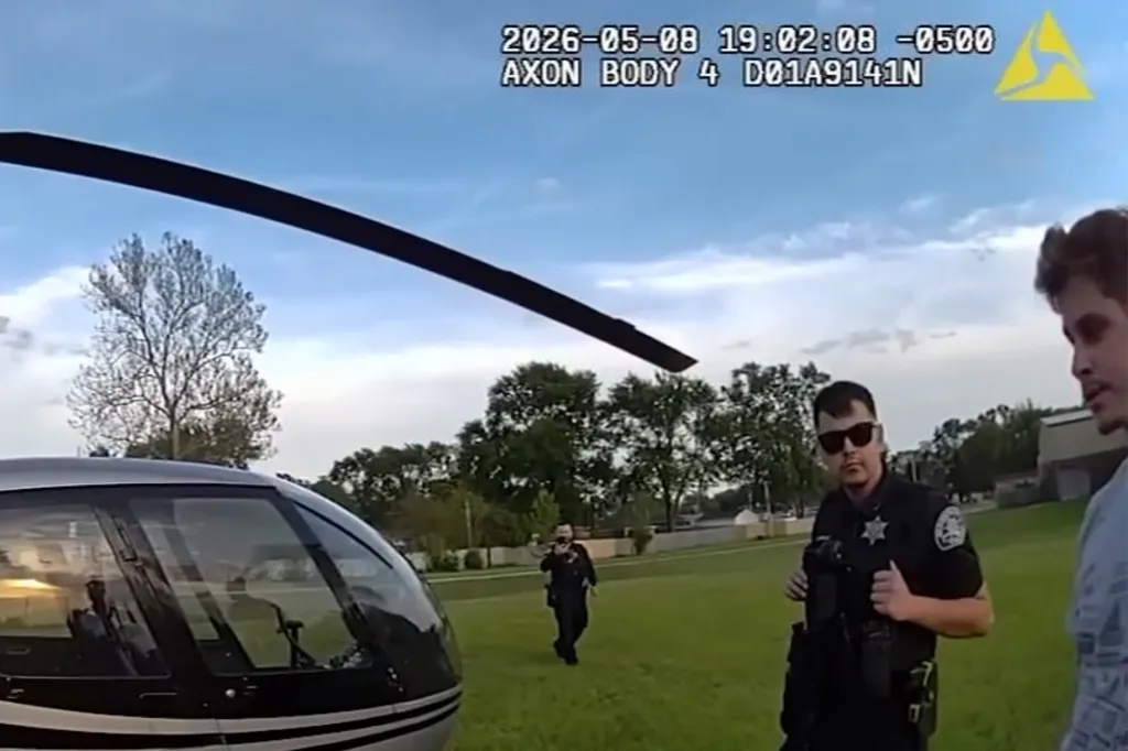 A police bodycam video shows a helicopter on a grassy field with a police officer and another man nearby.
