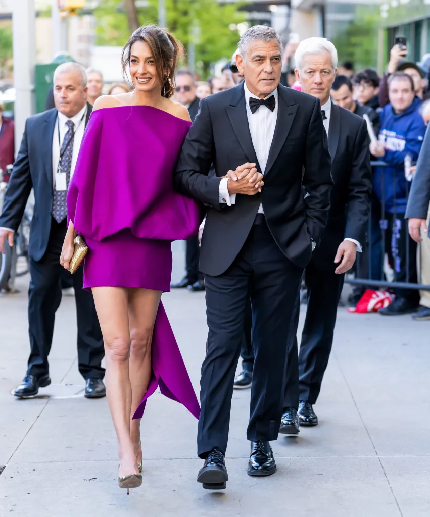 Amal Clooney in a purple dress and George Clooney in a tuxedo holding hands at the 51st Chaplin Award Gala.