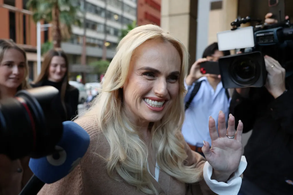 Rebel Wilson arriving at court on the first day of her defamation hearing in Sydney, smiling and waving to the crowd.