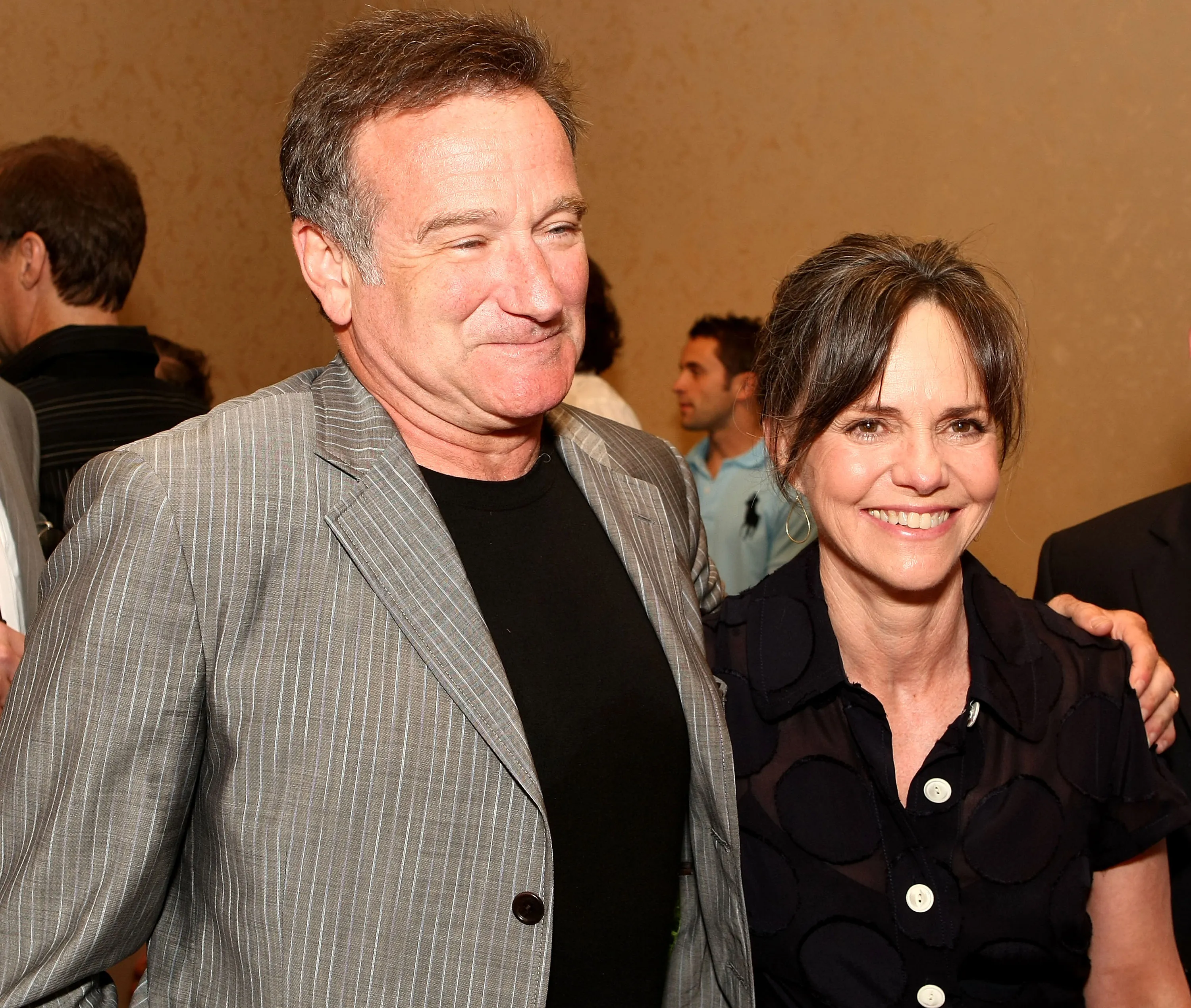 Actors Robin Williams and Sally Field posing together, with Williams looking right with a slight squint and Field smiling at the camera.