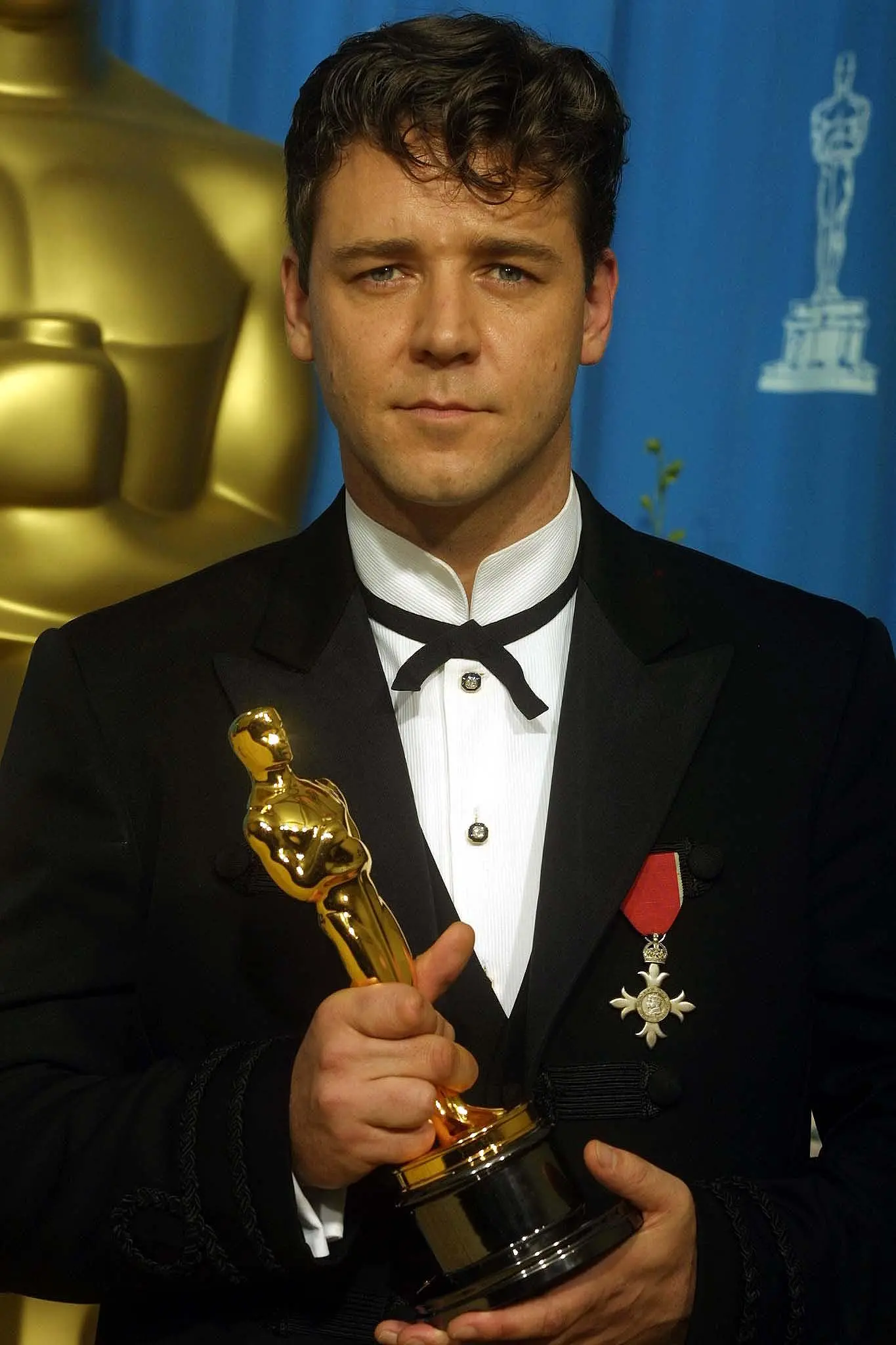 Russell Crowe in a tuxedo, holding his Best Actor Oscar.