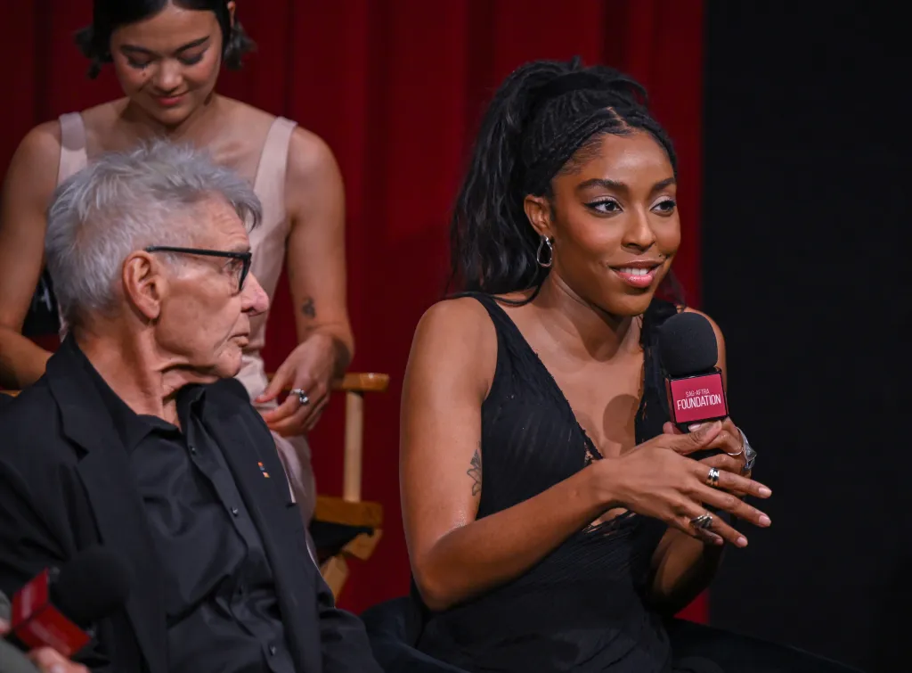 Jessica Williams speaking into a microphone, with Harrison Ford and Lukita Maxwell seated nearby, at the SAG-AFTRA Foundation Conversations event.