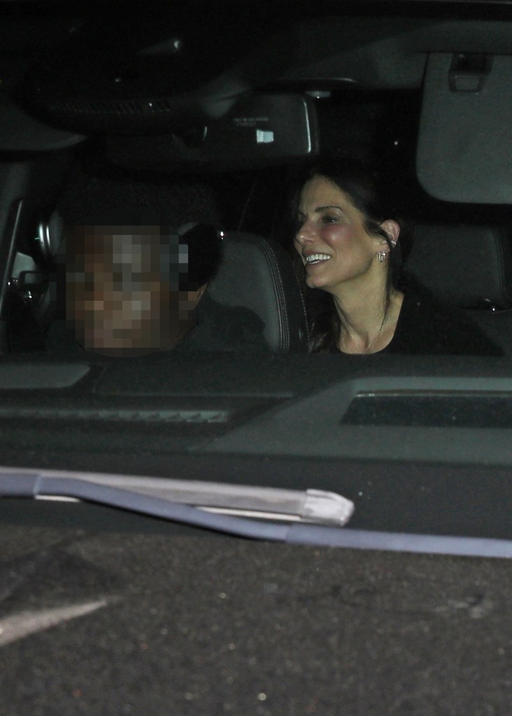 Sandra Bullock smiles while riding in a car at night with her son, Louis Bardo Bullock, whose face is pixelated.