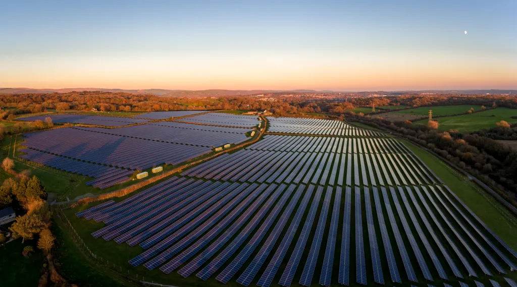 Aerial view of a solar energy farm at sunset in South Wales, UK.