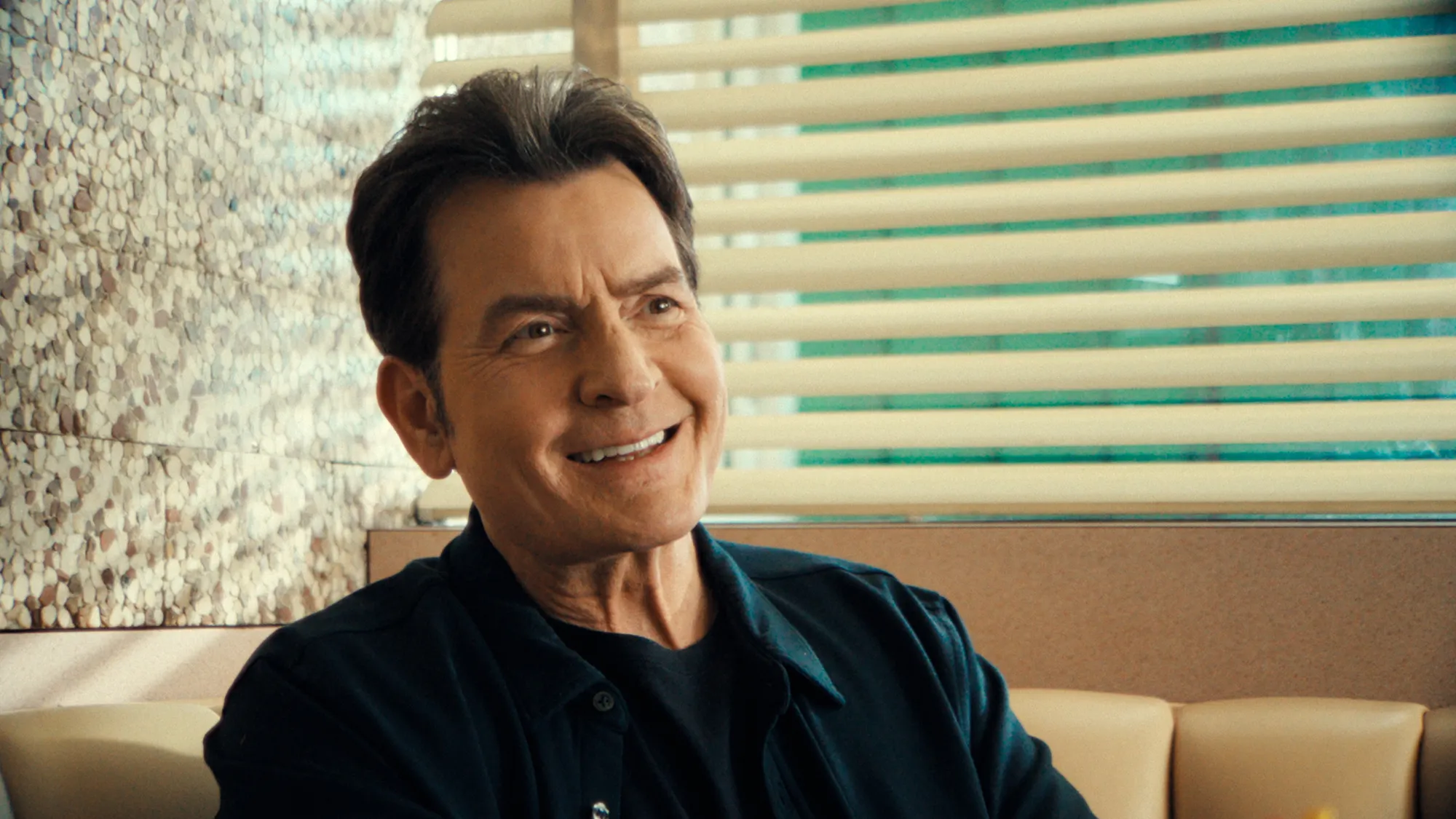 Charlie Sheen smiling and looking to the right.