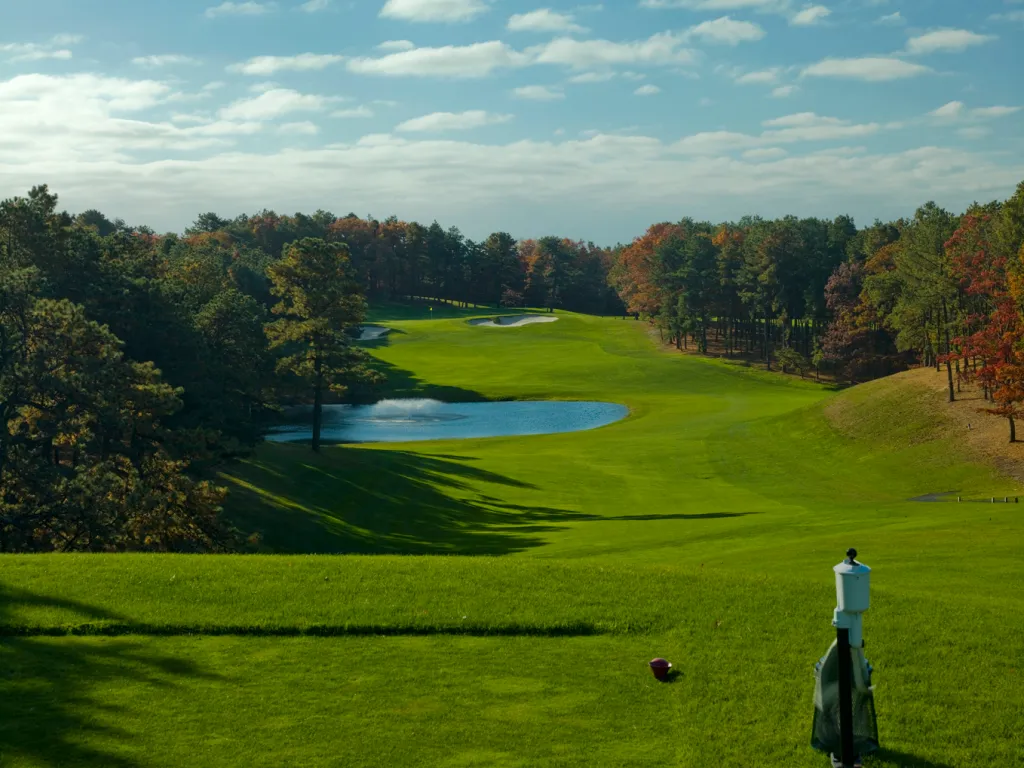 Hampton Hills Golf Course with a water hazard, green fairways, and autumn trees under a cloudy sky.
