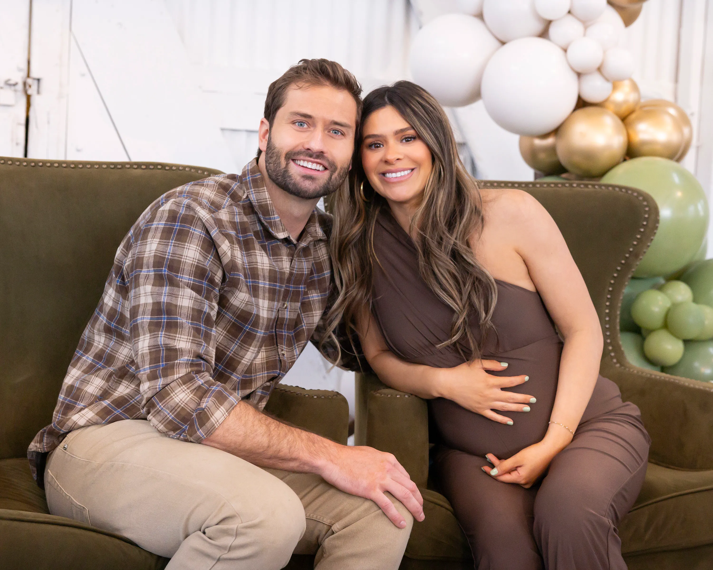 Taylor Frankie Paul and Dakota Mortensen smiling while seated on an olive green couch.