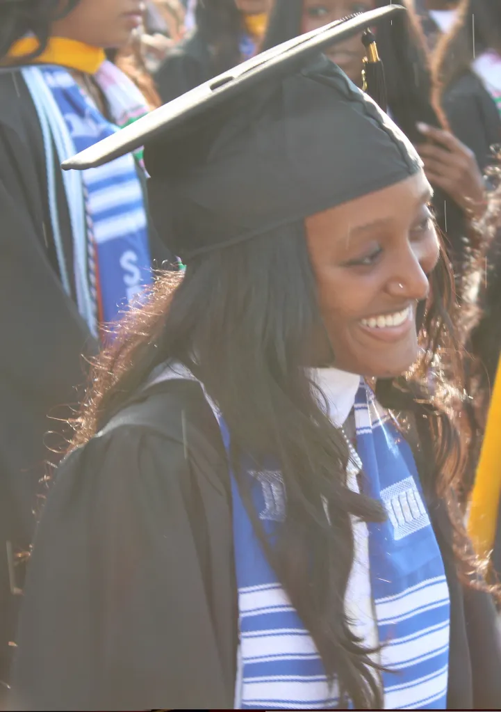 Zahara Jolie smiling in a graduation cap and gown, wearing a blue and white striped stole.