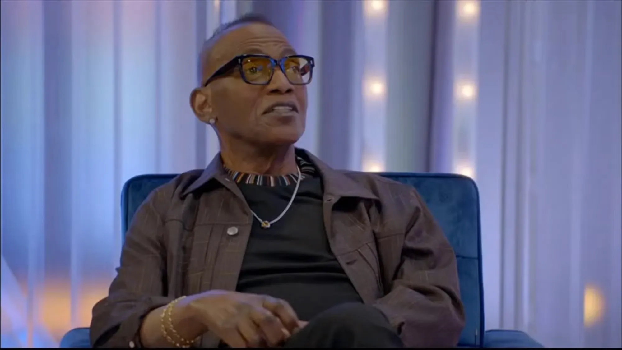 Randy Jackson in glasses, seated and looking up.