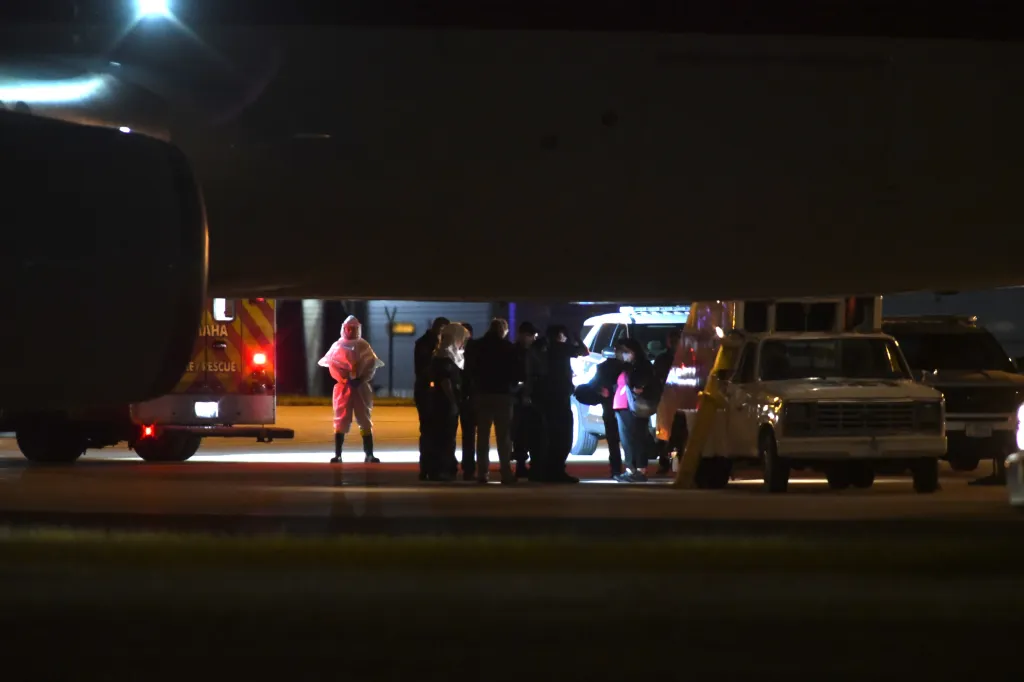 Passengers disembarking from a hantavirus-stricken cruise ship wearing protective gear.