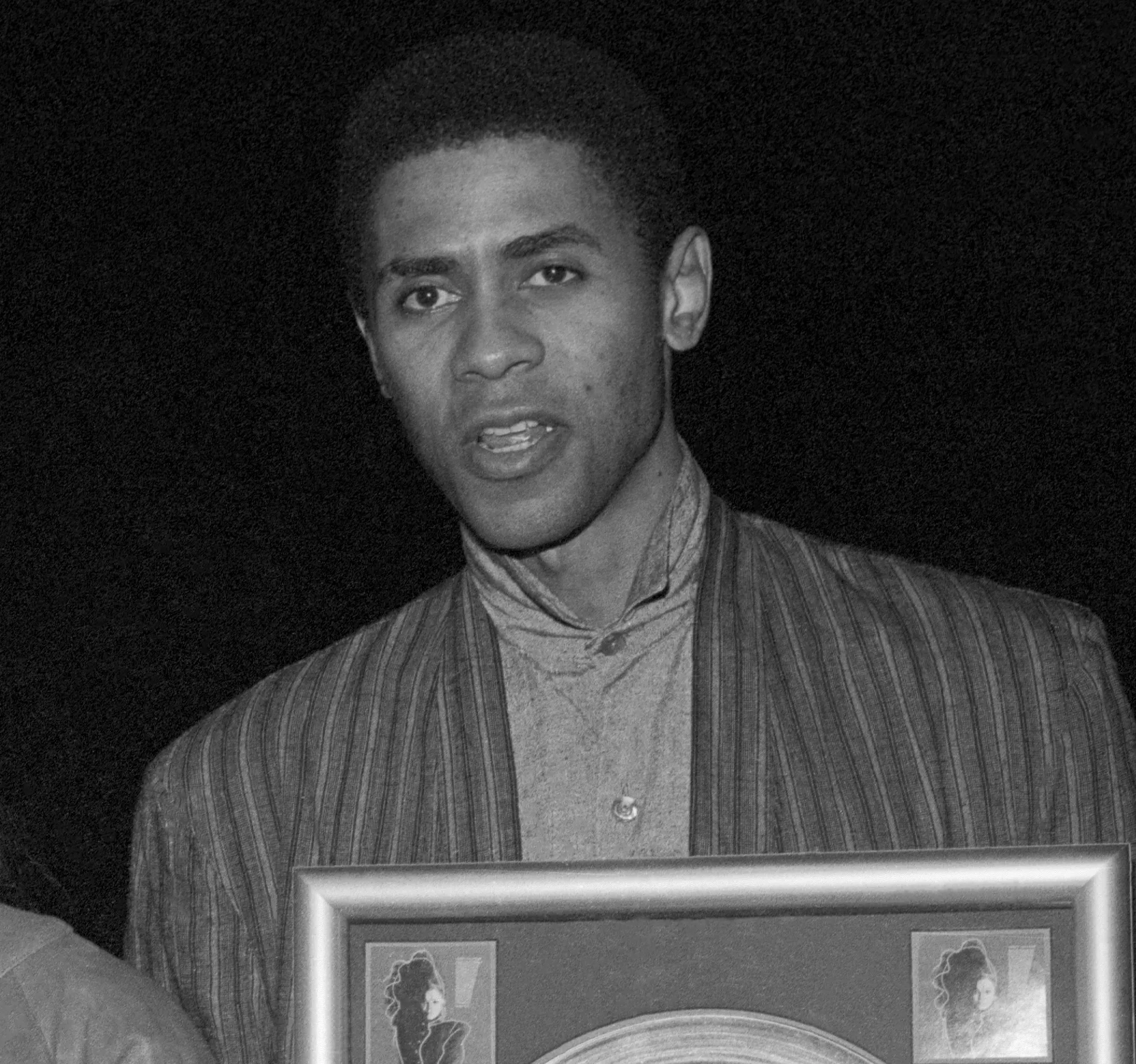 John McClain poses for a portrait holding a framed album.