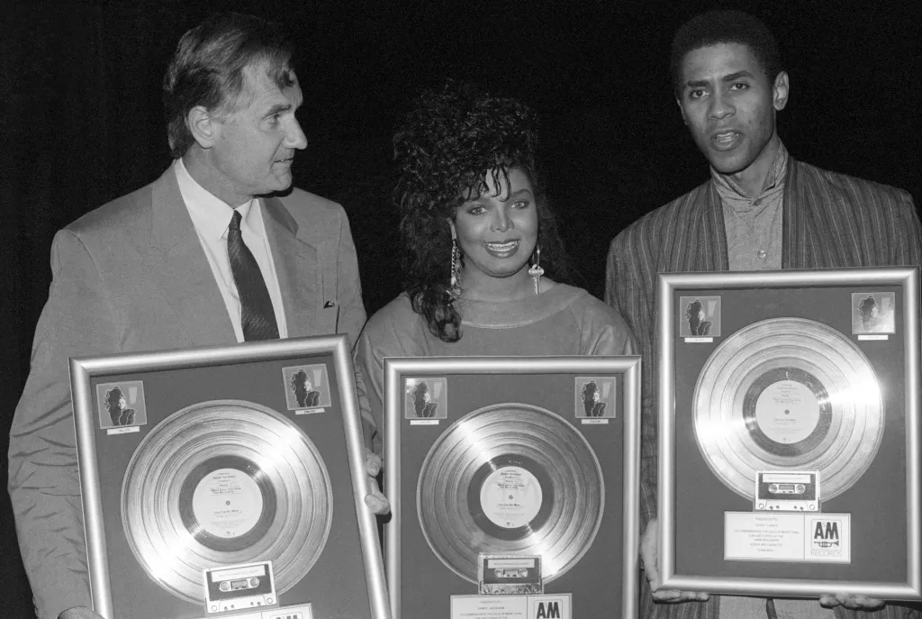Janet Jackson, Gil Friesen, and John McClain posing with three framed platinum records for the 