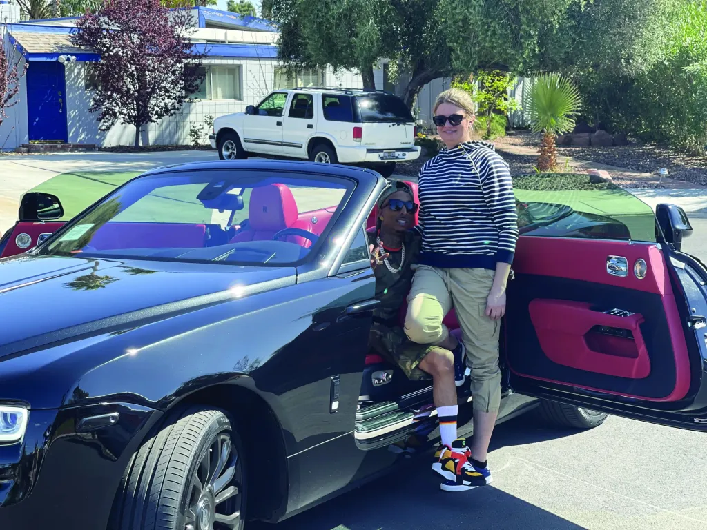 Amiee Bock posing with a man in a black luxury convertible.