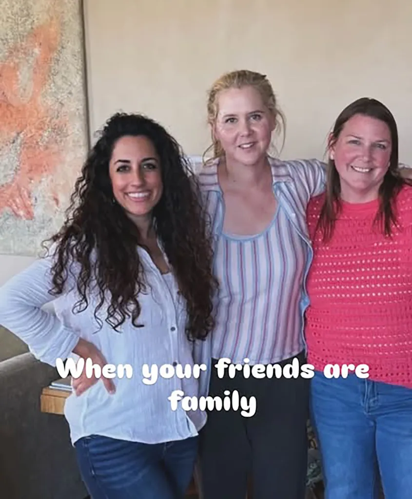 Amy Schumer with two friends, smiling.