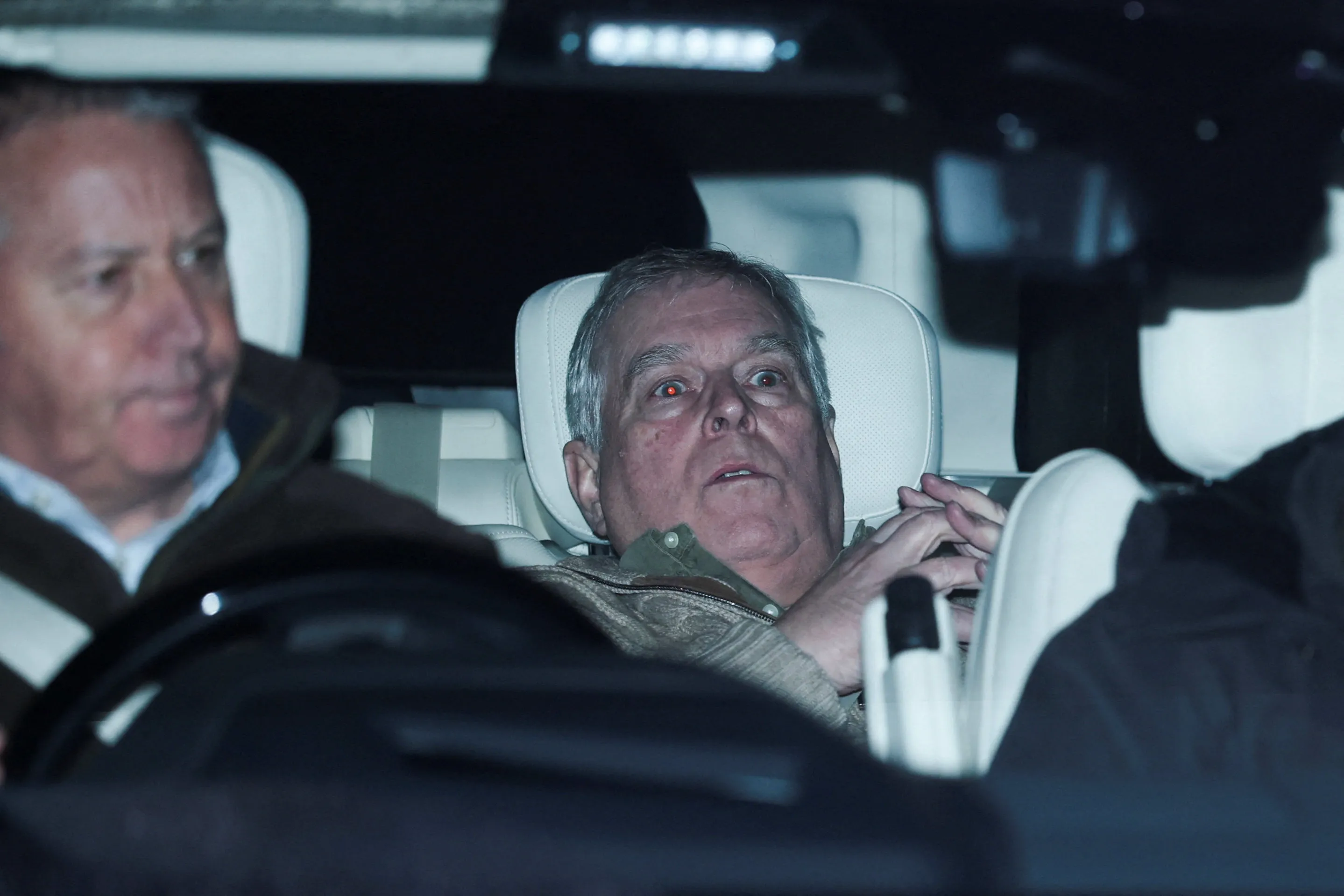 Andrew, formerly Prince Andrew, in the back seat of a vehicle with red-eye from flash.